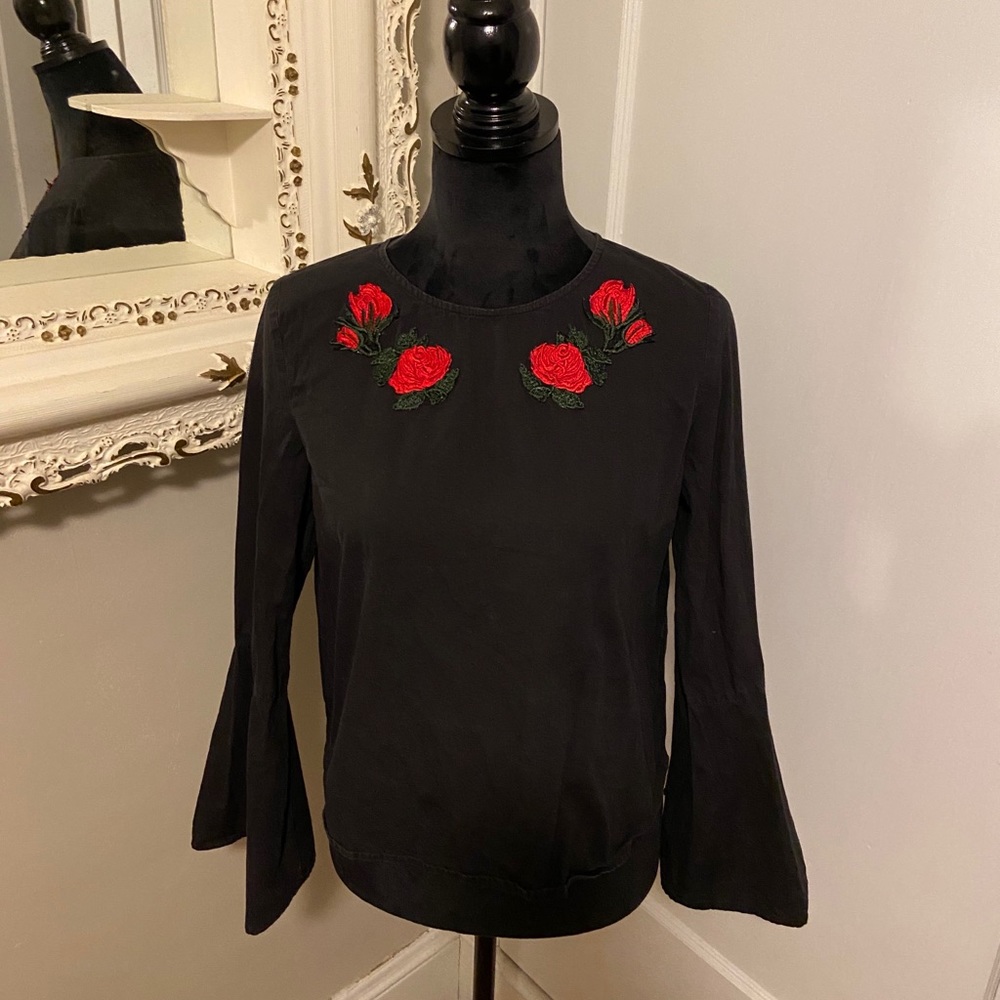 Black bell sleeve shirt with rose appliqués.
